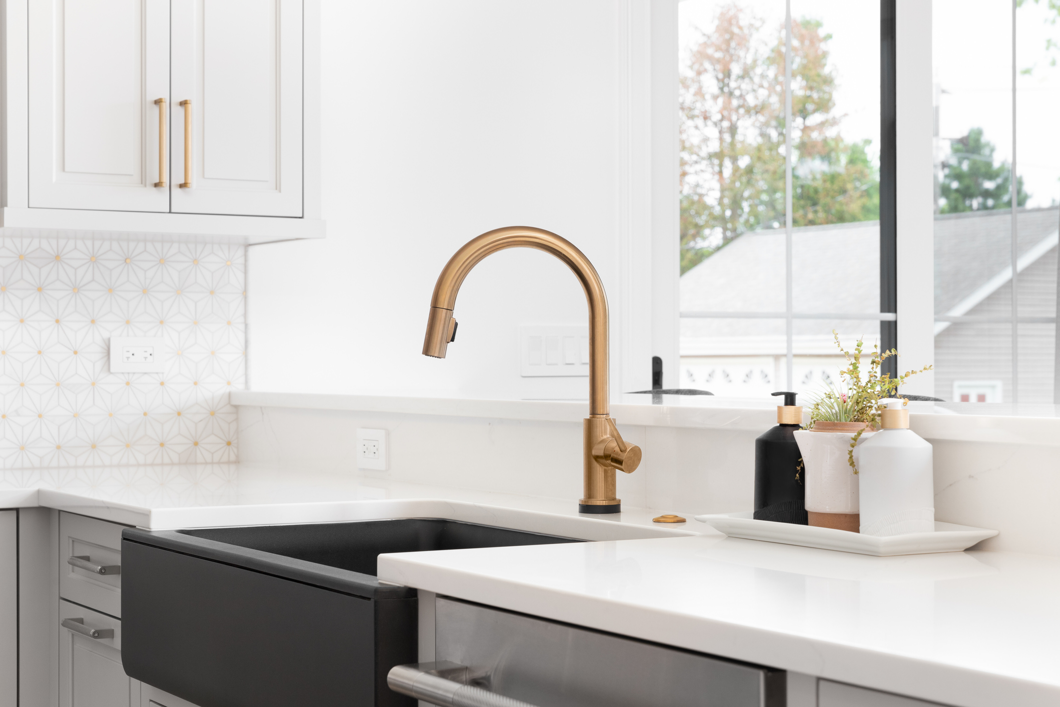 A modern kitchen sink with solid white stone complemented by gold accents shows the value of the right stone countertop in your kitchen.